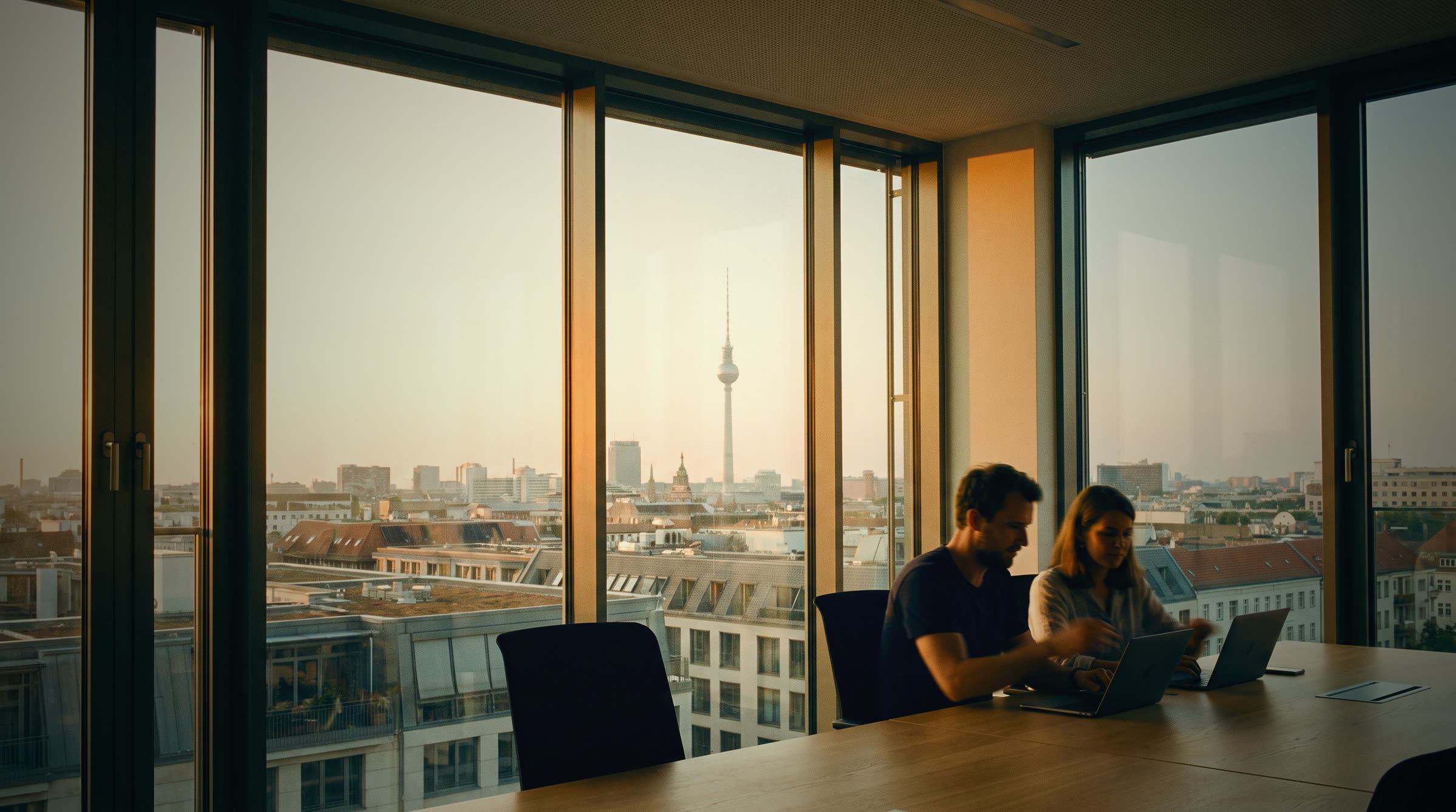 A Berlin office at golden hour, the TV tower beyond the windows