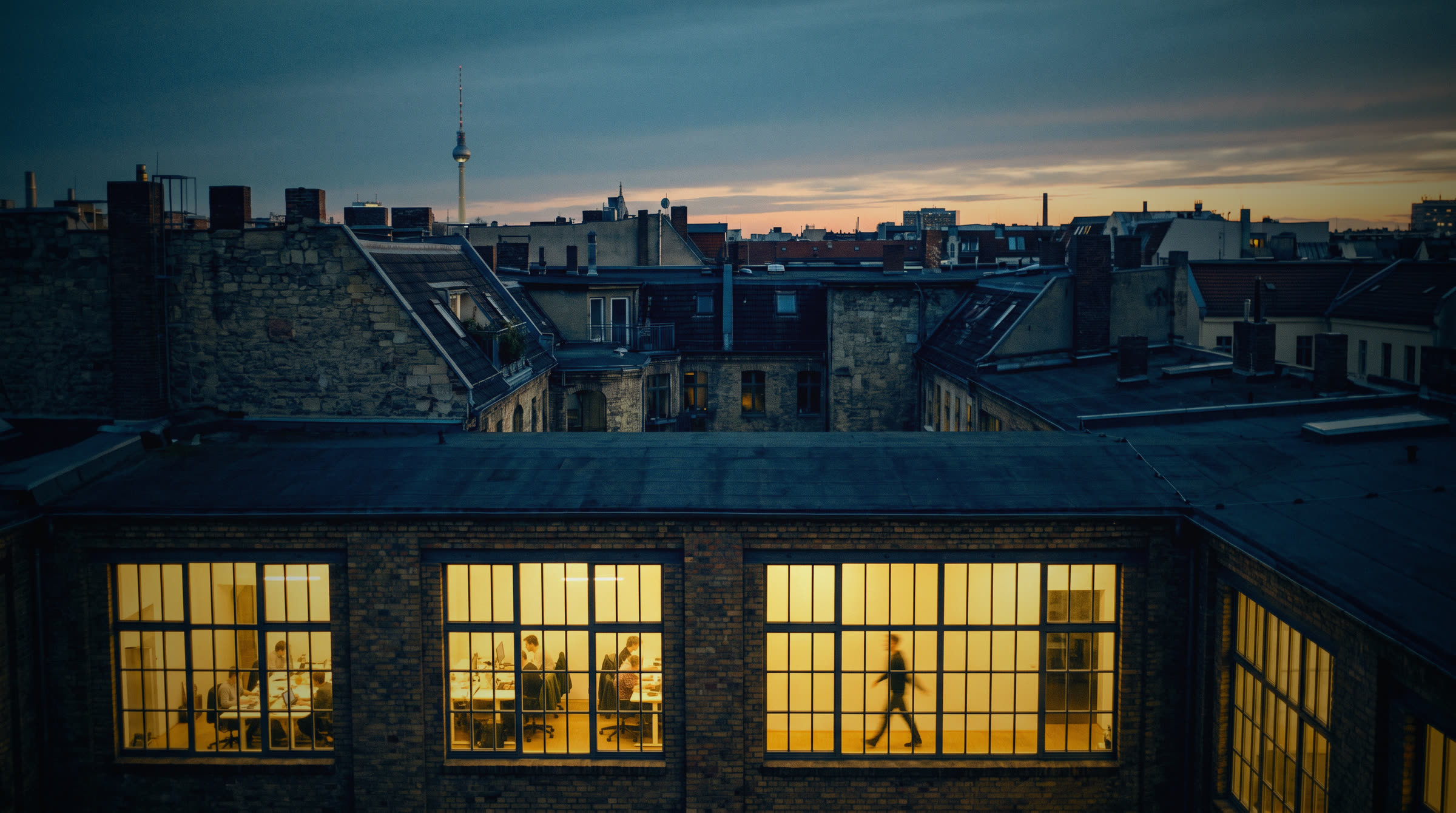 Lit office windows over the rooftops at dusk